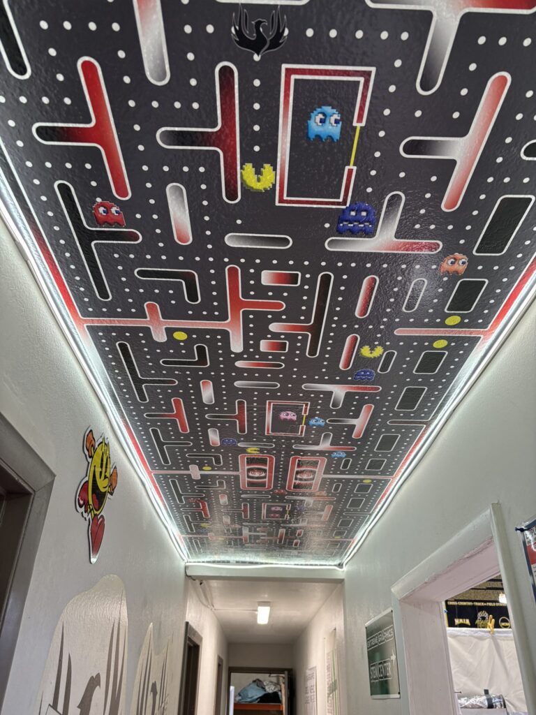 Printed arcade-maze ceiling wrap with LED edge lighting in the Extreme Graphics STEM Center hallway