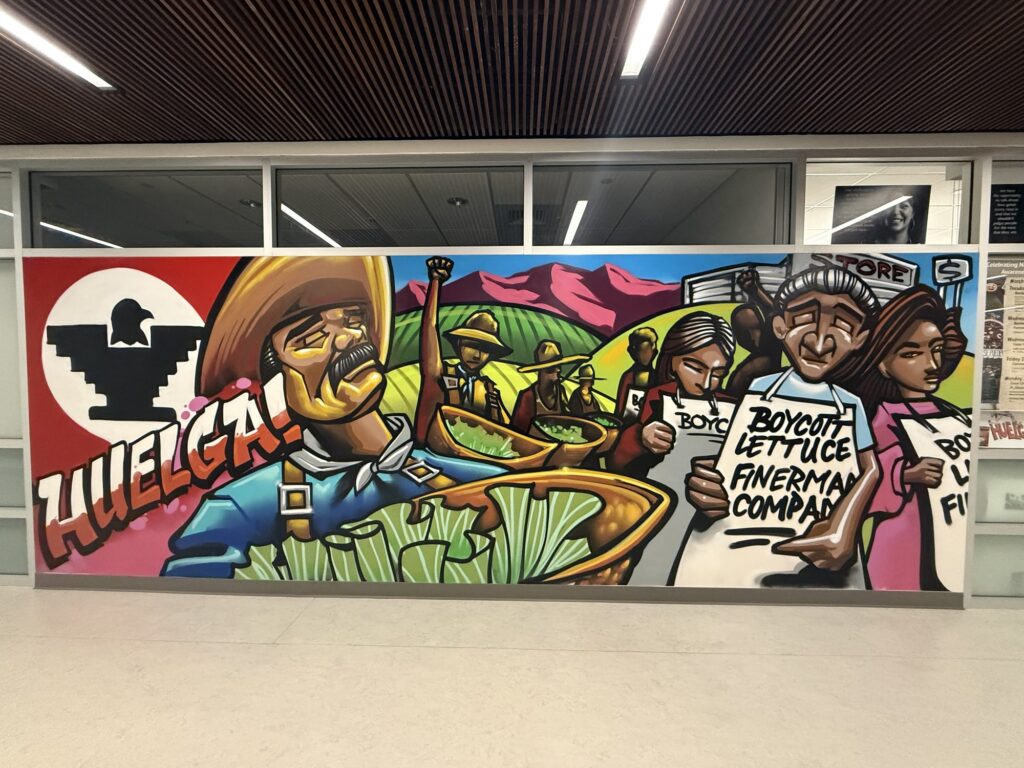 Large printed "Huelga" mural wall graphic installed in a hallway